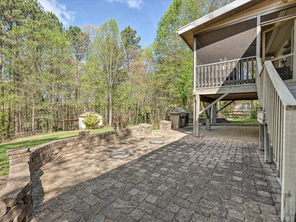 Covered paver patio with wall seating and outdoor grilling area below screened porch at 132 Gray Cliff Drive
