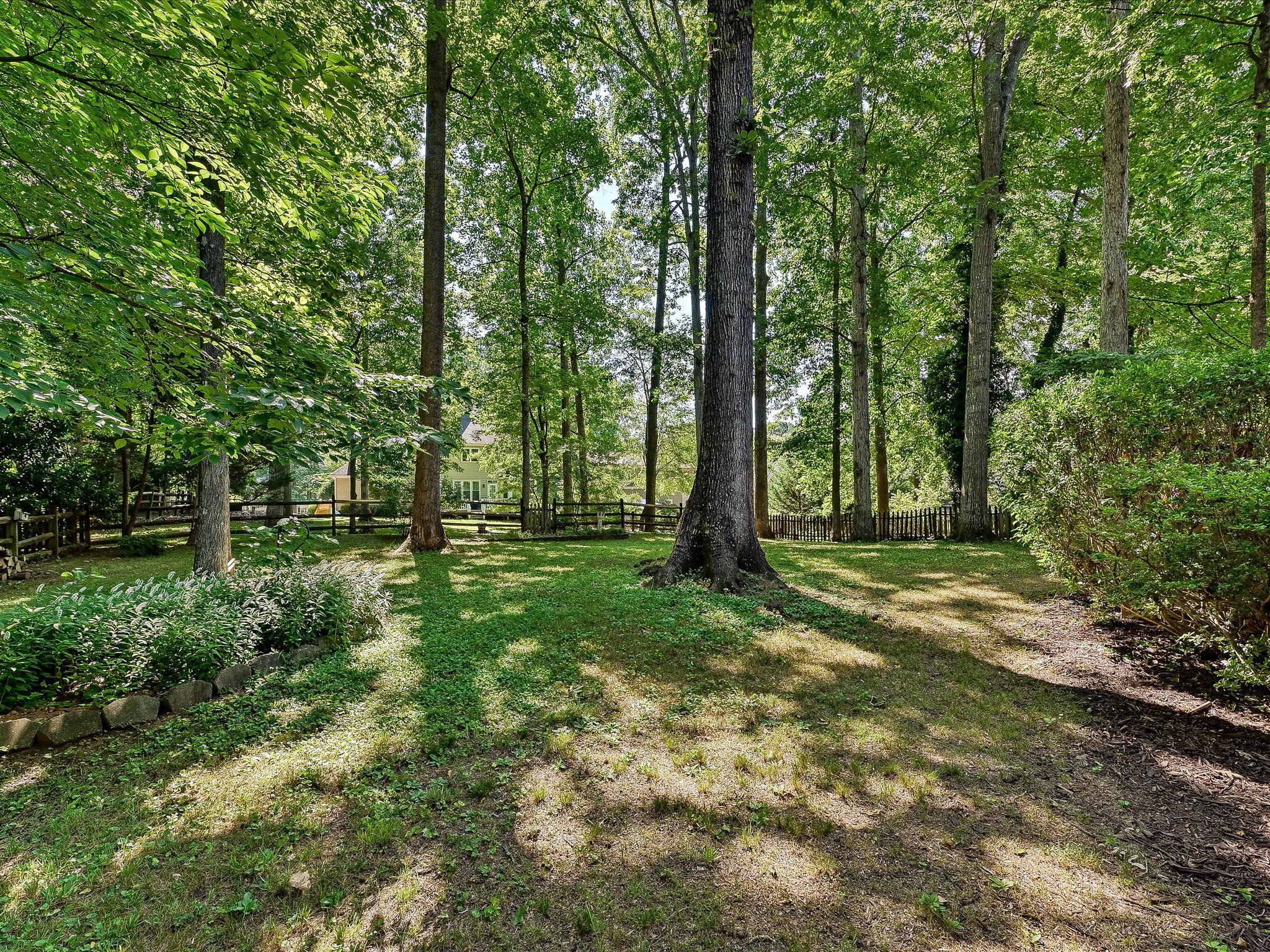Fenced backyard with mature trees at a Cedarfield home in Huntersville, NC